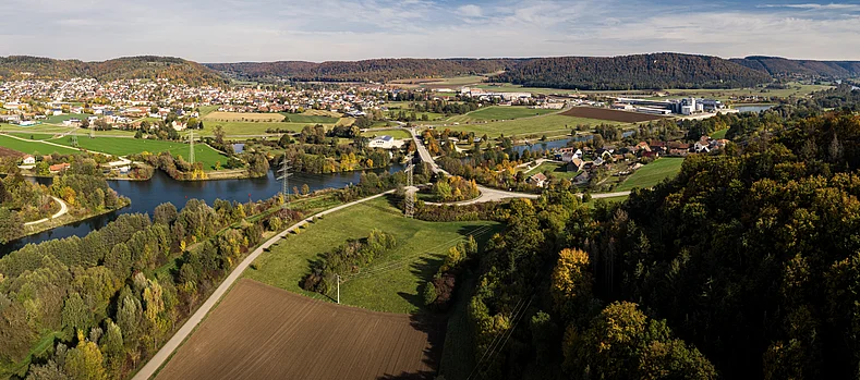 Luftaufnahme einer vielfältigen Kulturlandschaft mit Flüssen, Wäldern, Feldern und einer Ortschaft.